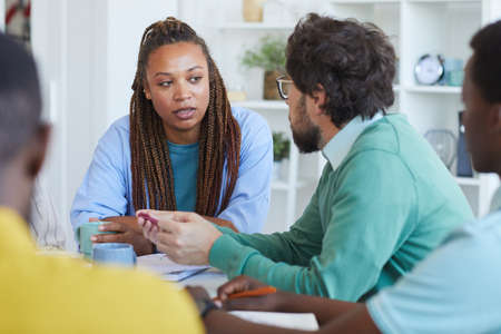 Portrait of contemporary African-American woman talking to colleagues during business meeting in officeの写真素材