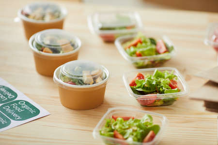 Background image of healthy food portions ready for packaging on wooden table in small food delivery...