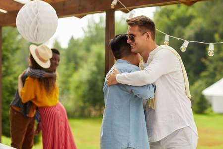 Waist up portrait of two young men hugging while greeting each other at outdoors party in Summer, copy spaceの写真素材