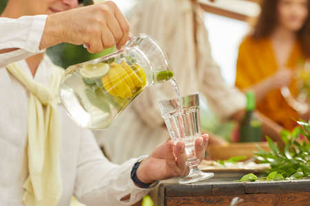 Close up of unrecognizable man pouring lemonade into glass cup while enjoying outdoor party in Summer, copy spaceの写真素材