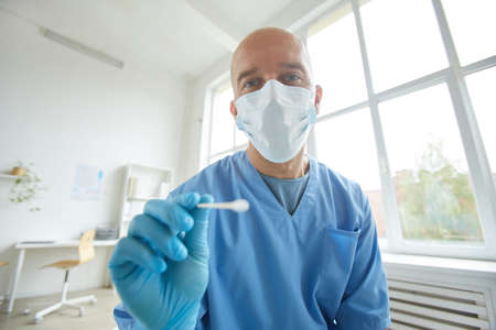 Horizontal medium portrait of general practitioner wearing protective mask and gloves going to take...
