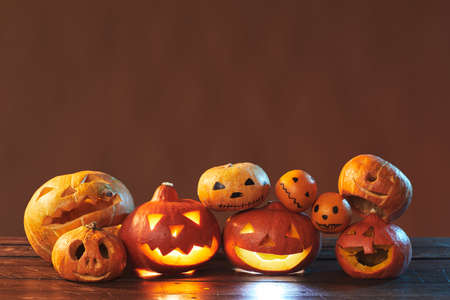 Horizontal studio shot of Halloween still life composition made of carved pumpkins and tangerines on brown background, copy spaceの写真素材