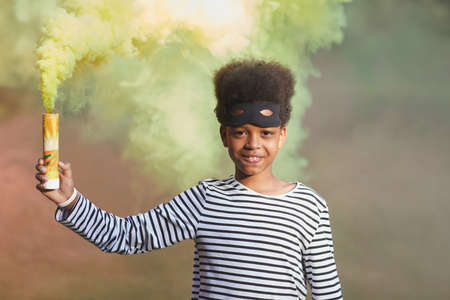 Waist up portrait of smiling African-American boy wearing Halloween costume and looking at camera...