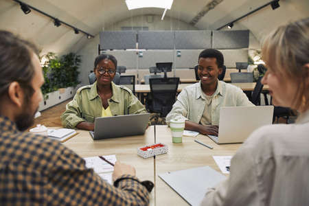 Portrait of two young African-American people smiling at business partners sitting across table during meeting in modern office, copy spaceの写真素材