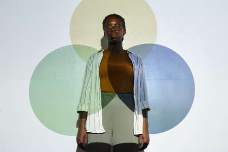 Waist up portrait of young African-American woman looking at camera while standing by projector...