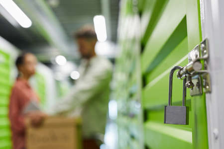 Close up of lock on self storage unit with blurred shape of couple in background, copy spaceの写真素材