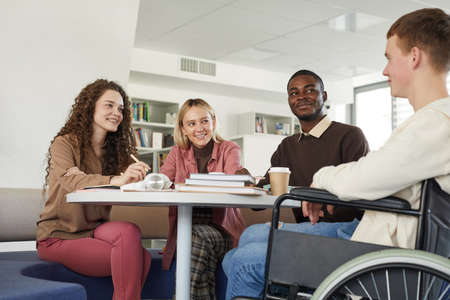 Low angle view at multi-ethnic group of students studying in college library featuring young man...