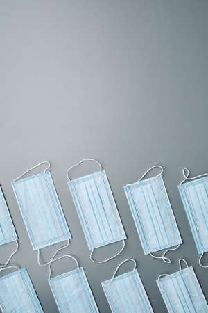 Top view background image of medical masks pattern laid out over grey background with blank space...