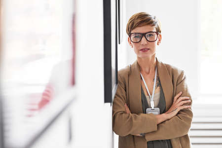 Waist up portrait of elegant creative woman looking at camera while standing with arms crossed...
