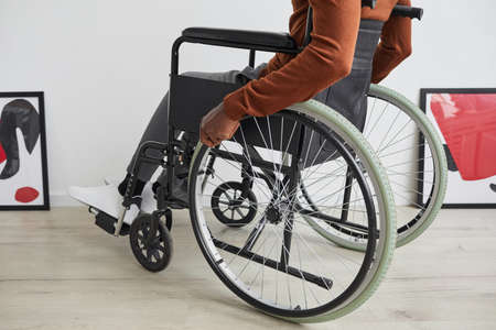 Low angle view at unrecognizable African-American man using wheelchair while exploring modern art gallery exhibition, copy spaceの写真素材