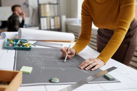 Cropped shot of unrecognizable female architect drawing blueprints and plans while working at desk...