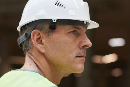Side view portrait of professional construction worker wearing helmet and looking away, copy space