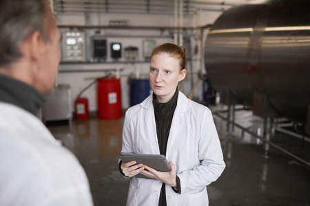 Waist up portrait of young woman talking to supervisor or manager while discussing work at food...