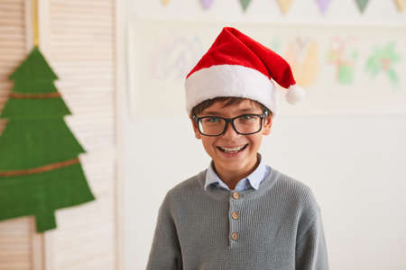 Portrait of smiling boy wearing Santa hat and looking at camera while enjoying art class on Christmas, copy spaceの写真素材