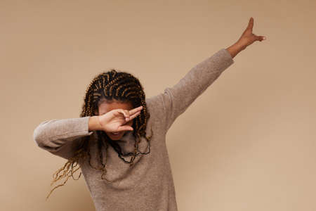 Waist up portrait of carefree African-American girl gesturing in studio, copy spaceの写真素材