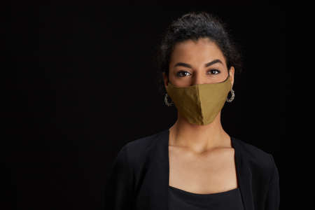 Close up portrait of elegant Middle-Eastern woman wearing face mask while posing against black background at party, copy spaceの写真素材