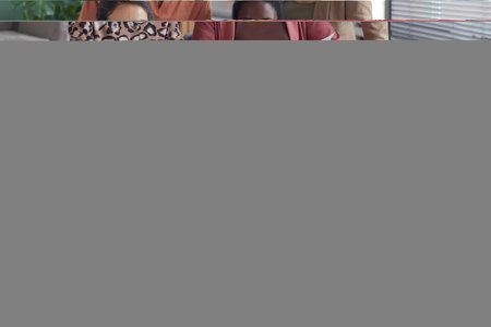 Multi-ethnic group of four contemporary businesswomen smiling at camera while posing in office
