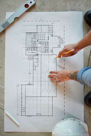 Top view close up of female construction worker pointing at blueprints while working in apartment building, copy spaceの写真素材