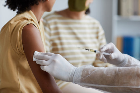Close up of unrecognizable male nurse vaccinating African-American child against covid in clinic,...