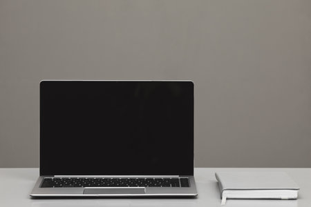 Graphic background image of laptop with blank screen on desk against ultimate gray background, mock...