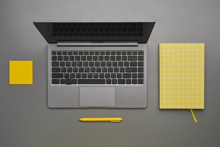 Graphic gray and yellow background of laptop with business accessories at desk, flatlay top down...