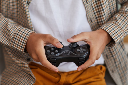 Close up of teenage African-American boy holding gamepad while playing videogames at home, copy spaceの写真素材