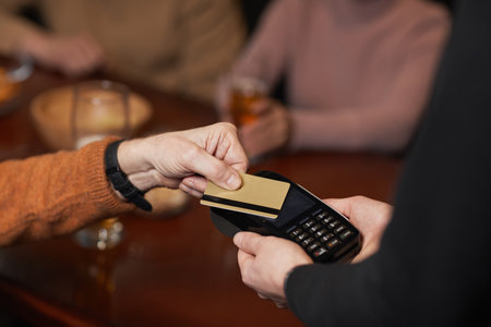 High angle close up of unrecognizable man paying with credit card, focus on hands holding card over terminal, copy spaceの写真素材