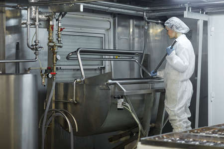 Wide angle view female worker using mixing machine at clean food production factory, copy spaceの写真素材