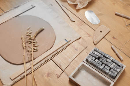 Background image of raw plant imprint ceramics on wooden table in pottery workshop, copy space