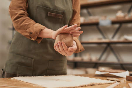 Warm toned close up of young woman shaping clay while making ceramics in pottery workshop, small business concept, copy spaceの写真素材