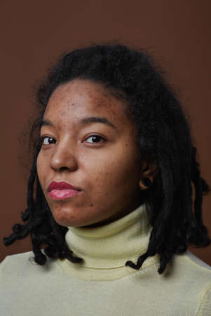 Vertical close up portrait of real African American woman looking at camera while posing against...
