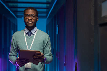 Waist up portrait of African American data engineer looking at camera while working with...