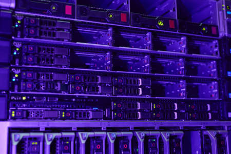 Futuristic background image of rack servers in supercomputer network lit by blue and violet light,...
