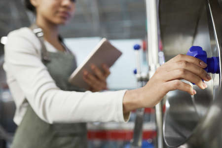 Close up of African American female worker opening valves at industrial factory, copy space