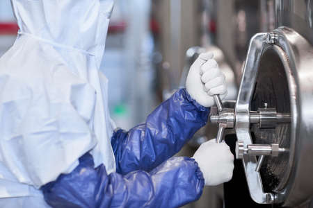Cropped side view portrait of male worker wearing protective suit while operating equipment at...