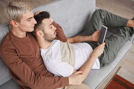 Young Gay Couple Relaxing on Couch at Homeの写真素材