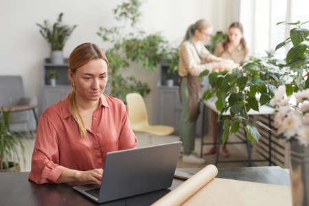 Portrait of successful young businesswoman using laptop in flower shop while managing small business, copy spaceの写真素材