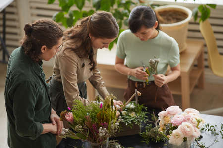 High angle view at group of florists arranging floral compositions in workshop, copy spaceの写真素材