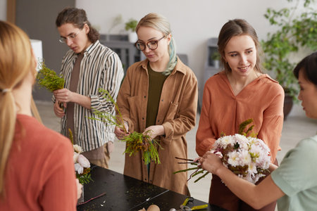 High angle portrait of diverse group of young people attending class on floral art in florists workshopの写真素材