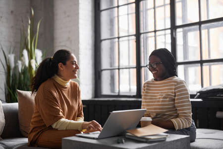 Side view portrait of Middle-Eastern businesswoman talking to colleague while discussing project in...