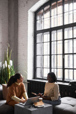 Vertical portrait of Middle-Eastern businesswoman talking to colleague while discussing project in modern office interior, copy spaceの写真素材