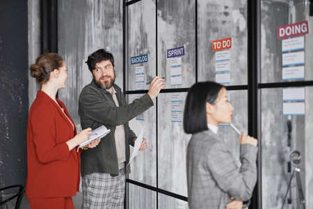 Diverse group of business people standing by glass wall while planning project in modern office, copy spaceの写真素材