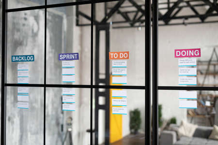Background image of task lists or kanban board for business planning on glass wall in graphic office interior, copy spaceの写真素材