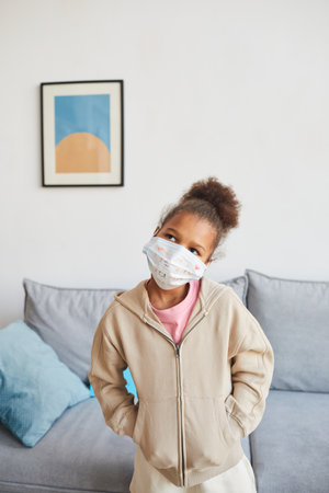 Vertical waist up portrait of cute African-American girl wearing mask at home on Fathers day and looking away, copy spaceの写真素材