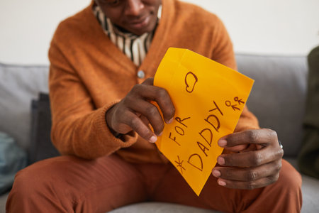 Close up of African-American man opening letter for daddy as handmade gift for Fathers day, copy spaceの写真素材