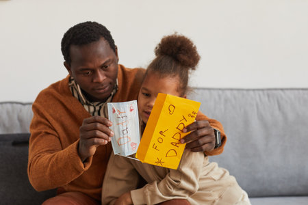 Portrait of cute African-American girl presenting handmade gift to dad on Fathers day, copy spaceの写真素材