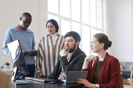 Side view portrait of diverse group of business people using computer while planning project in...