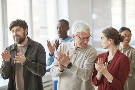 Diverse group of business people applauding at meeting or seminar, focus on young businesswoman...