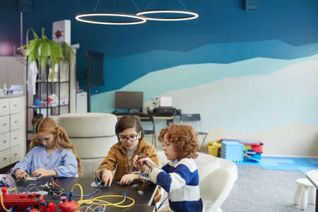 High angle portrait of three cute children building robots during engineering class in development...