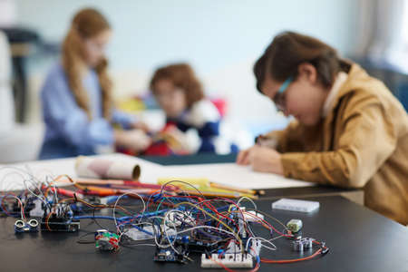Group of children building robots in engineering class at school, focus on wires and electric circuits in foreground, copy spaceの写真素材